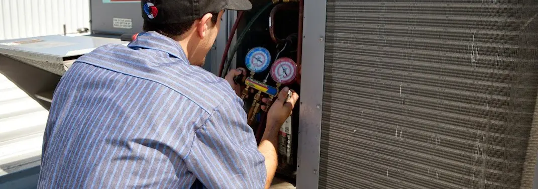 HVAC technician servicing a condenser unit in Mercedes