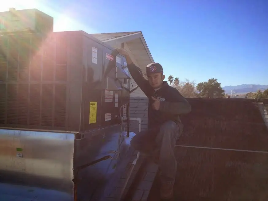 HVAC technician performing Heat Pump Repair on a rooftop unit in Mercedes